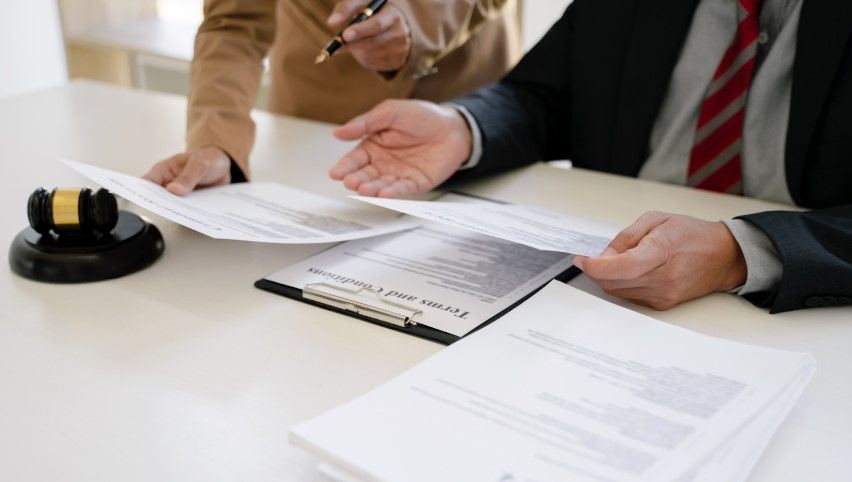 Two people are reviewing and discussing copyright applications at a desk, with a gavel, clipboard, and paperwork visible—considering special handling options to expedite registration.